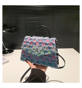 Détail du sac à main en denim à carreaux avec nœud argenté et bords effilochés