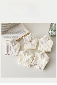 Flat lay of five pairs of white summer socks with lace ruffles and bow details