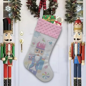 Pink and white nutcracker Christmas stocking with gifts hanging on a festive door