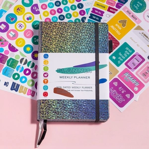 Flat lay of shimmering weekly planner with colorful productivity stickers and elastic strap