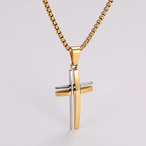 Macro detail of a two-tone gold and silver layered hollow cross pendant on a box chain