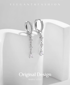 Detail of silver drop earrings with shimmering crystals on minimalist curved display