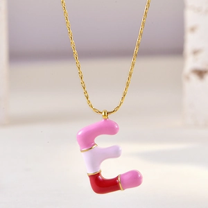 Macro detail of gold chain necklace featuring pink and purple enamel letter E pendant