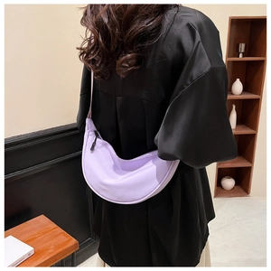 Close-up of a lilac nylon crescent bag worn by a model in a cozy indoor setting
