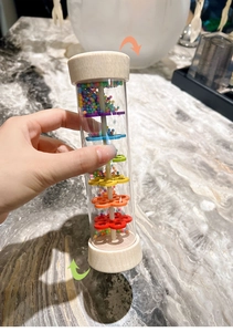 Detail of wooden rainmaker toy with transparent tube and colorful beads inside