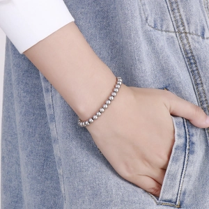 Gros plan d'un bracelet en perles d'acier inoxydable argenté porté avec du denim