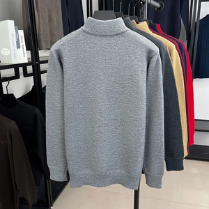 Detailansicht der grauen Strickstruktur und des Rippsaums eines Herren-Winterpullovers