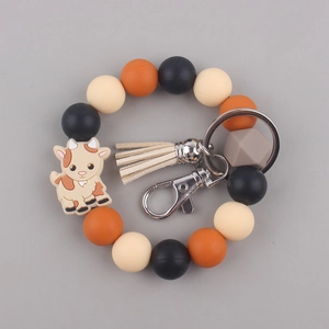 Detail of beaded keychain bracelet with orange silicone beads and cute cartoon goat charm