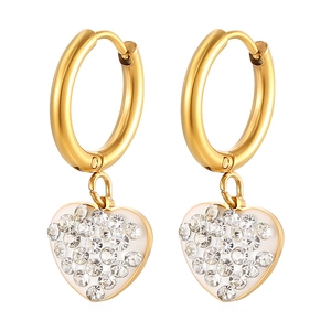 Macro detail of golden stainless steel hoop earrings with crystal-studded heart charms