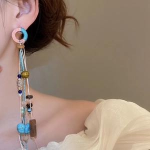 Detail of bohemian tassel earrings with colorful beads and woven rings on a model