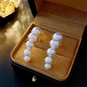 Detailed macro view of French vintage pearl earrings with gold plating and five white pearls
