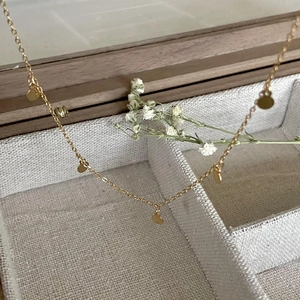 Close-up of a gold minimalist disc necklace on a beige jewelry box with baby's breath