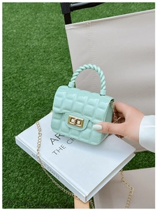 Detail of mint green quilted jelly bag with gold chain and woven handle in nature