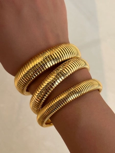 Close-up of golden 18k plated Tubogas style elastic snake bracelet on woman's wrist