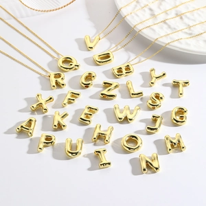 Macro view of gold plated A-Z letter pendants showing polished metal texture and shine