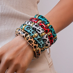 Close-up of colorful leopard print acrylic bracelets with golden metal spacers on wrist