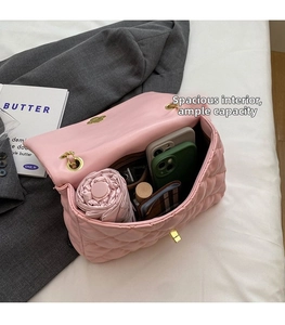 Spacious interior of pink quilted leather bag holding a phone, wallet, and umbrella