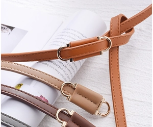 Macro shot of thin PU leather belts in brown and khaki with golden metal buckles