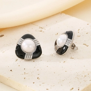 Detailed macro of black resin earrings with pearls on beige stone and silk fabric