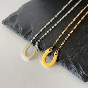 Close-up of horseshoe-shaped necklaces in gold and silver finishes on a textured stone