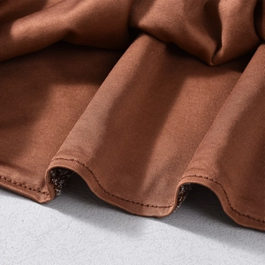Gros plan sur un tissu marron à paillettes avec bords à volants et détails de couture