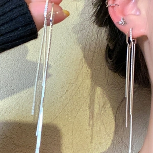 Detailed view of silver-plated long tassel earrings with sparkling zircon on ear model.