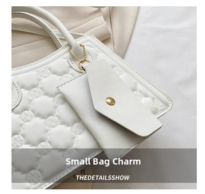 Close-up of white quilted leather crossbody bag with circular embossed logo and gold hardware