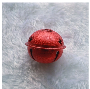 Detail of a 4cm red matte metal star bell with hollow cutouts on white plush background