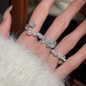 Detail view of a pearl and zircon star open ring on a model with white sweater