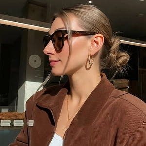 Golden C-shaped hoop earrings with zircons worn by a model in warm natural light
