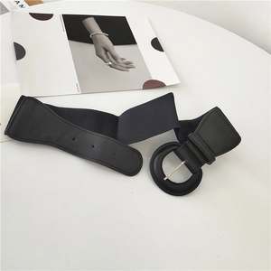 Elastic wide black waist belt with round faux leather buckle on minimalist table setting