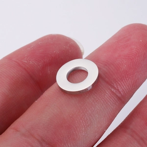 Polished silver stainless steel hollow circular pendant held between fingers