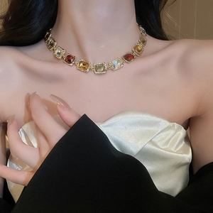 Close-up of vintage gold necklace with multi-colored square gemstones worn by a model