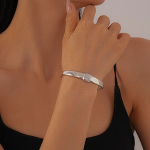 Detail eines silbernen geometrischen Edelstahlarmreifs mit Zirkonia am Handgelenk des Models