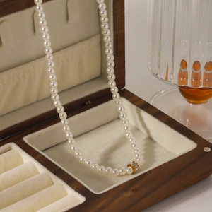 Close-up of pearl necklace with a gold-plated rhinestone circle pendant in a wooden box