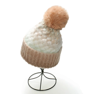 Close-up of thick winter knit beanie with large fluffy pompom and ribbed cuff detail