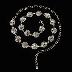 Detail of silver bohemian metal waist chain featuring carved coins and bell on black background
