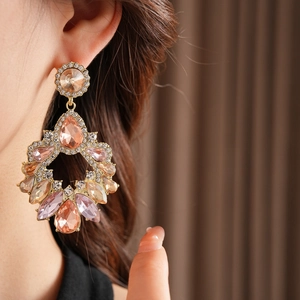 Détail de boucles d'oreilles dorées avec pierres roses et champagne sur un mannequin