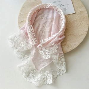 Detailed view of pink seersucker fabric with delicate white lace trim on a stone plate