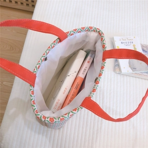 Close-up of floral canvas tote bag with red strap handle and metal snap button closure