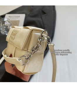 Détail du sac à main en cuir tressé crème avec chaîne argentée et gaufrage