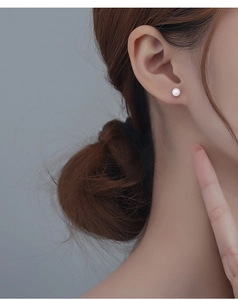 Close-up of minimalist s999 silver ear studs featuring 5mm white pearl on model ear