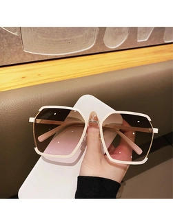 Detail of white semi-rimless sunglasses with brown gradient lenses and metal hinge mechanism