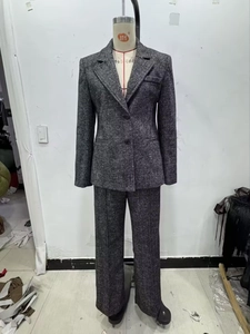 Dettaglio della giacca da abito in tweed grigio scuro con chiusura a doppio bottone e tessuto