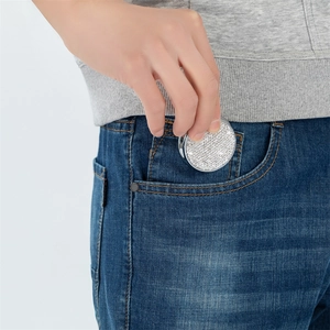 Close-up of portable rhinestone medicine box being put into a denim jeans pocket