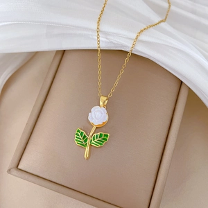 Close-up of a gold flower necklace with white petals and green leaves on a jewelry box