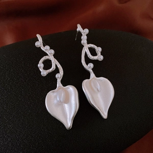 Macro detail of silver leaf texture and pearl accents on vintage style earrings