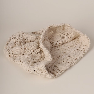 Close-up of beige crochet lace beanie featuring intricate hollow floral knit patterns