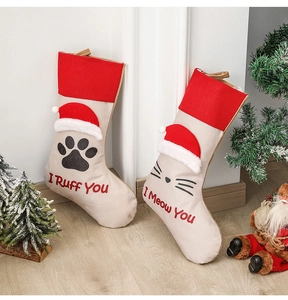 Detail of red and beige Christmas stockings featuring cat and dog paw prints on a white wall