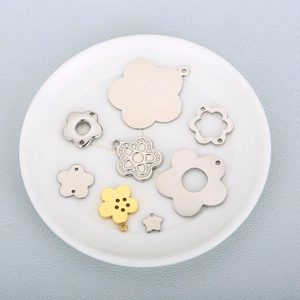 Polished stainless steel flower pendants in gold and silver finish on a ceramic plate